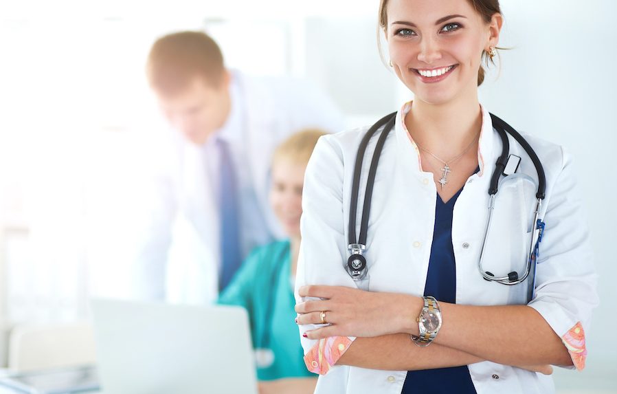 Doctor smiling with staff in background